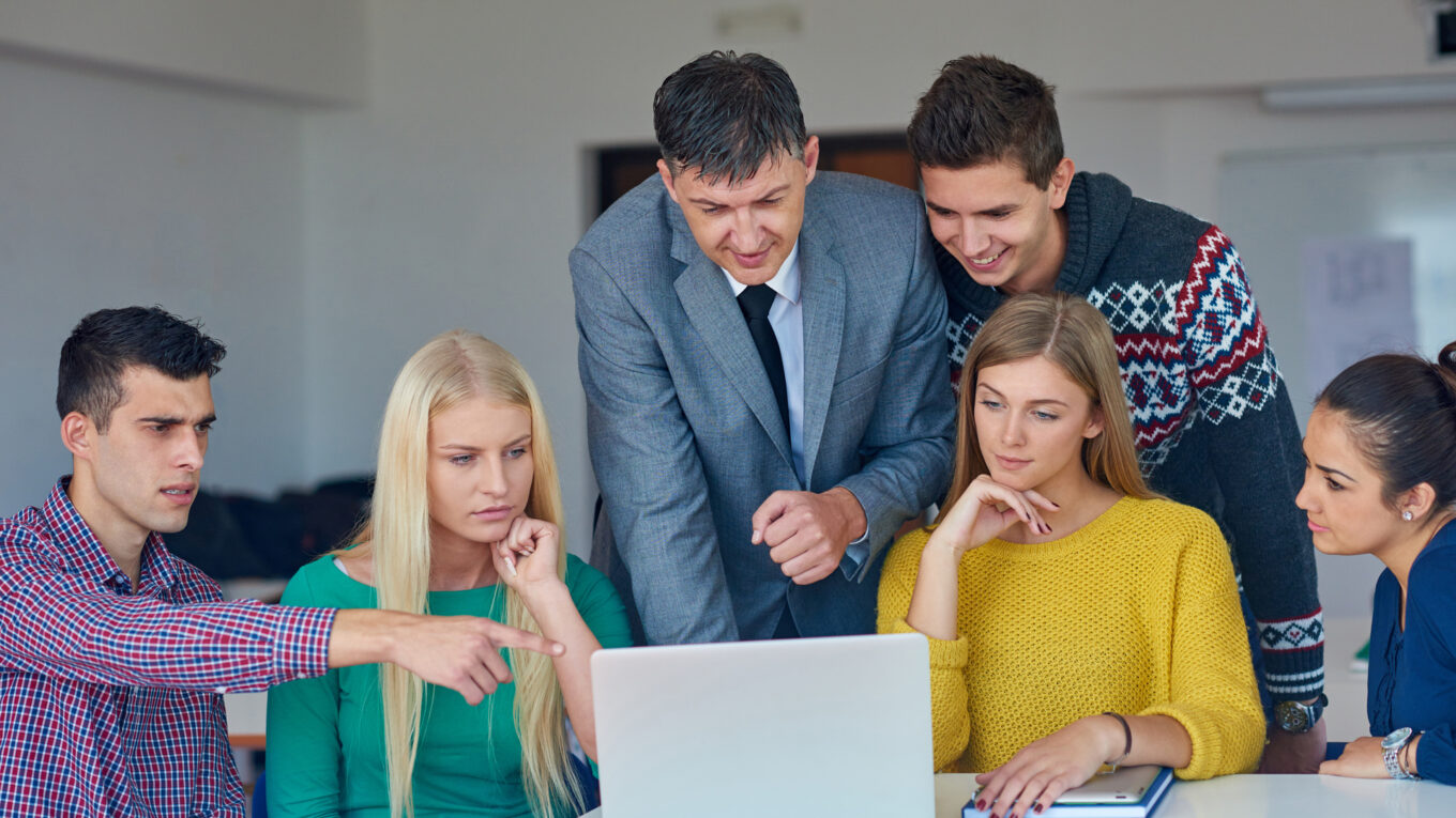 Studenci i wykładowca Uniwersytetu Łódzkiego korzystający z laptopa